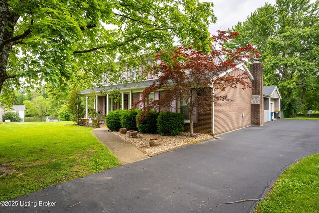7003 Red Plum Ter, Pewee Valley, KY 40056 - view of property hidden behind natural elements with a front lawn, brick siding, and driveway