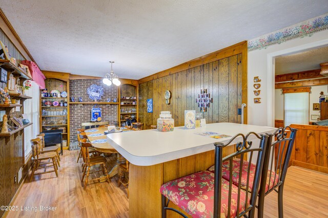 7003 Red Plum Ter, Pewee Valley, KY 40056 - kitchen featuring light wood-style floors, wooden walls, a textured ceiling, light countertops, and hanging light fixtures
