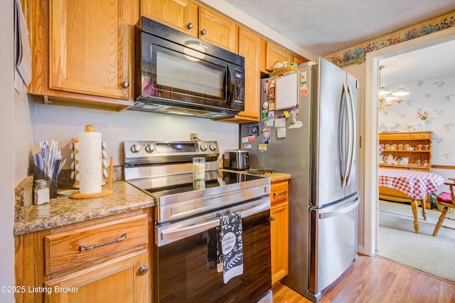 7003 Red Plum Ter, Pewee Valley, KY 40056 - kitchen featuring stainless steel appliances, light wood-style floors, a textured ceiling, light stone counters, and a chandelier