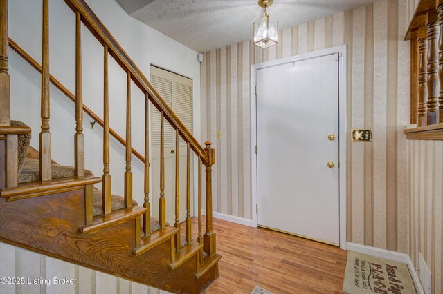 7003 Red Plum Ter, Pewee Valley, KY 40056 - entrance foyer featuring light wood finished floors, wallpapered walls, stairs, a textured ceiling, and baseboards