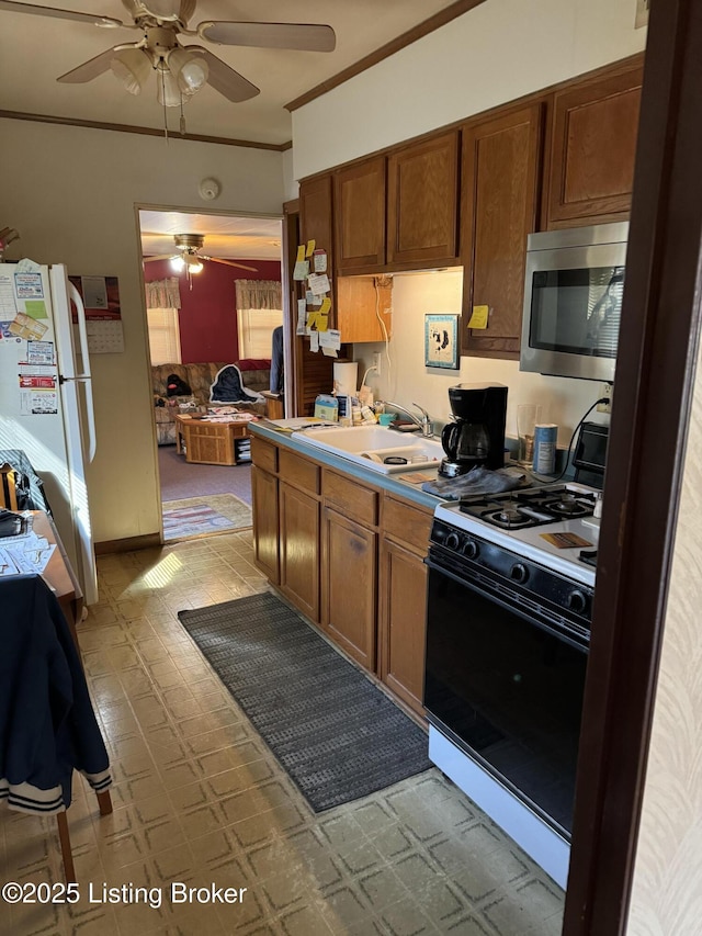 216 Bonnie Ln, Louisville, KY 40218 - kitchen featuring gas range, stainless steel microwave, a ceiling fan, a sink, and freestanding refrigerator