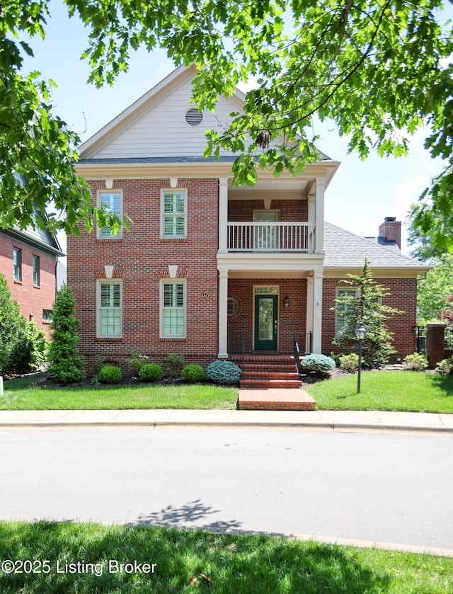 view of front facade featuring a balcony, a chimney, and brick siding