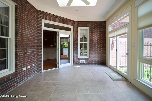 unfurnished sunroom with a ceiling fan and a skylight