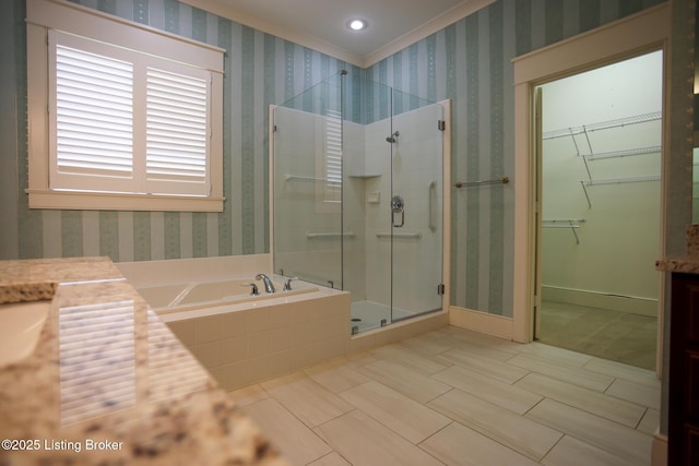 bathroom with a stall shower, a bath, a walk in closet, and baseboards