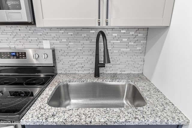 530-532 E Burnett Ave, Louisville, KY 40217 - kitchen view of backsplash, a sink, stainless steel microwave, white cabinets, and light stone countertops