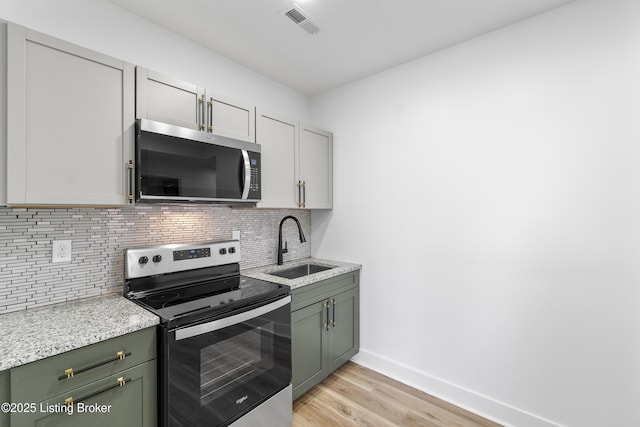 530-532 E Burnett Ave, Louisville, KY 40217 - kitchen featuring appliances with stainless steel finishes, green cabinets, a sink, baseboards, and light wood-style flooring