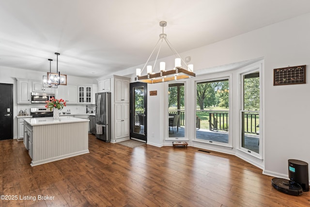 1609 Tall Oaks Dr, Jeffersonville, IN 47130 - kitchen with stainless steel appliances, a chandelier, light countertops, glass insert cabinets, and dark wood-style flooring