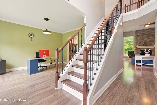 566 Wooded Falls Rd, Louisville, KY 40243 - staircase with wood finished floors, baseboards, a ceiling fan, a high ceiling, and a stone fireplace