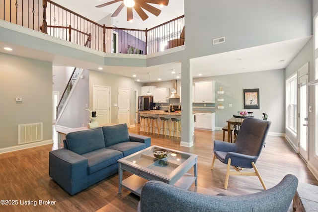 566 Wooded Falls Rd, Louisville, KY 40243 - living room featuring a ceiling fan, stairs, light wood-type flooring, baseboards, and a towering ceiling
