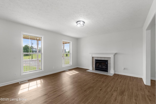 228 Schlaefer Way, Rineyville, KY 40162 - unfurnished living room with a tile fireplace, dark wood-style floors, a textured ceiling, and baseboards