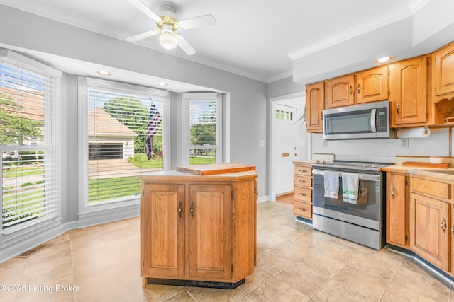 kitchen with stainless steel appliances, ornamental molding, light countertops, ceiling fan, and a center island