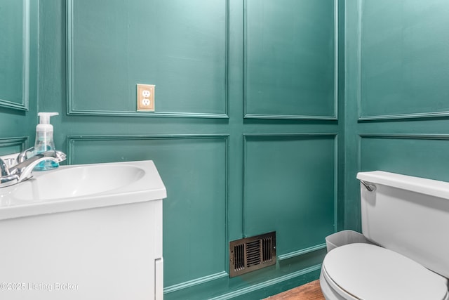 bathroom with toilet, vanity, and wood finished floors