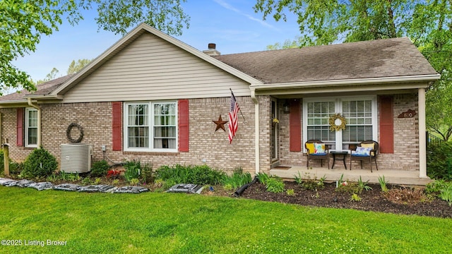 ranch-style home featuring brick siding, a front lawn, cooling unit, and a shingled roof