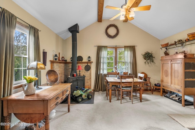 dining area with carpet, a wood stove, plenty of natural light, and ceiling fan