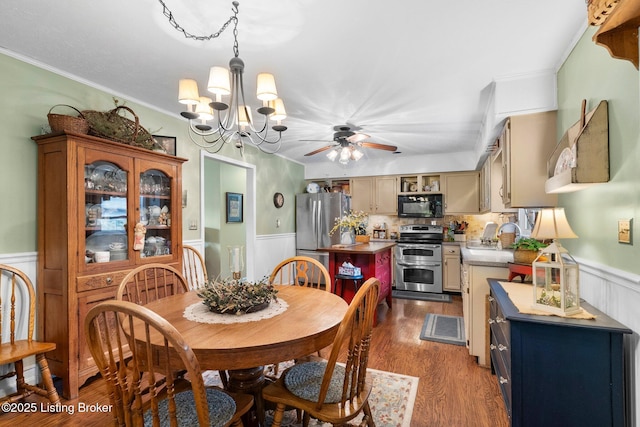 dining room featuring wainscoting, ceiling fan, dark wood-style floors, a chandelier, and crown molding