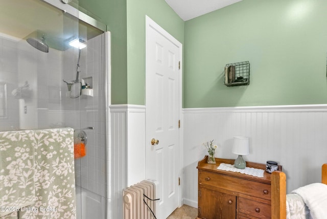 full bath with tiled shower, radiator heating unit, and wainscoting
