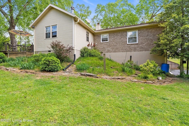 view of side of home featuring a yard, a chimney, and brick siding