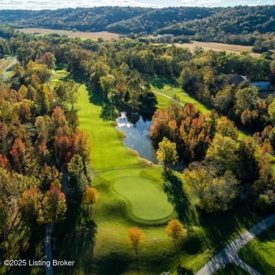 drone / aerial view of a large body of water, a golf club, and a forest