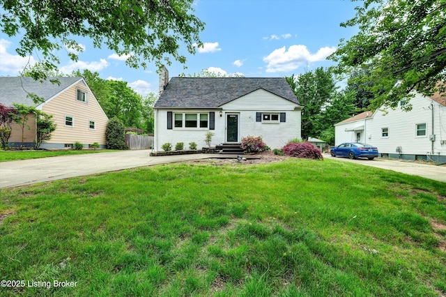 view of front of home with entry steps, a chimney, concrete driveway, and a front lawn