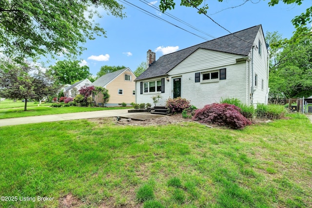 view of front of home with a chimney, a front yard, and brick siding