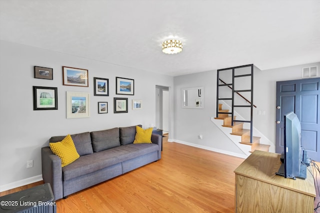 living area featuring stairway, light wood finished floors, and baseboards