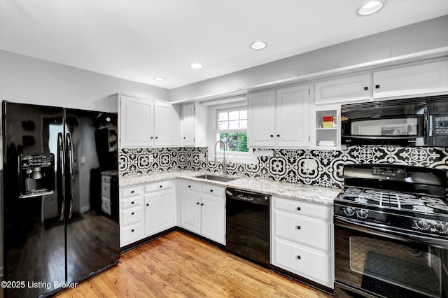kitchen with black appliances, a sink, light wood-style flooring, white cabinetry, and tasteful backsplash