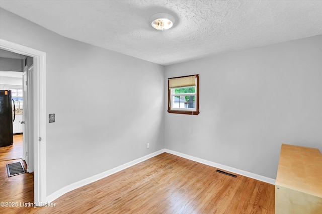 unfurnished room with wood finished floors, baseboards, and a textured ceiling