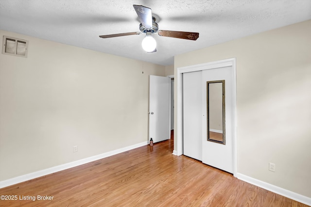 unfurnished bedroom featuring light wood-style flooring, a closet, baseboards, and ceiling fan