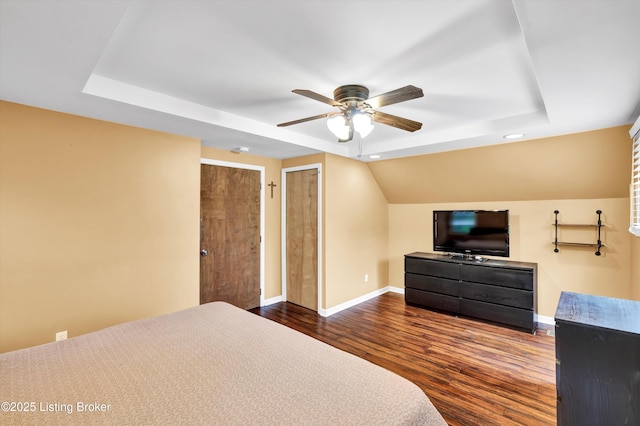 bedroom with a tray ceiling, dark wood-style floors, baseboards, recessed lighting, and ceiling fan