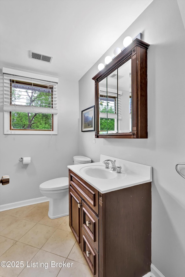 half bathroom featuring toilet, plenty of natural light, vanity, and baseboards
