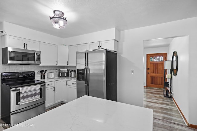 2700 Bagby Way, Louisville, KY 40216 - kitchen with stainless steel appliances, white cabinetry, backsplash, and wood finished floors