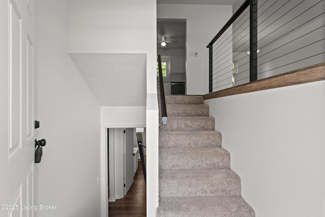 stairway with a ceiling fan and wood finished floors