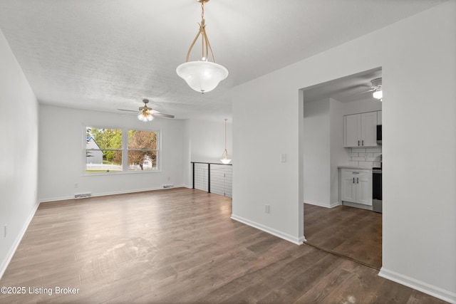 unfurnished living room with a ceiling fan, wood finished floors, and baseboards
