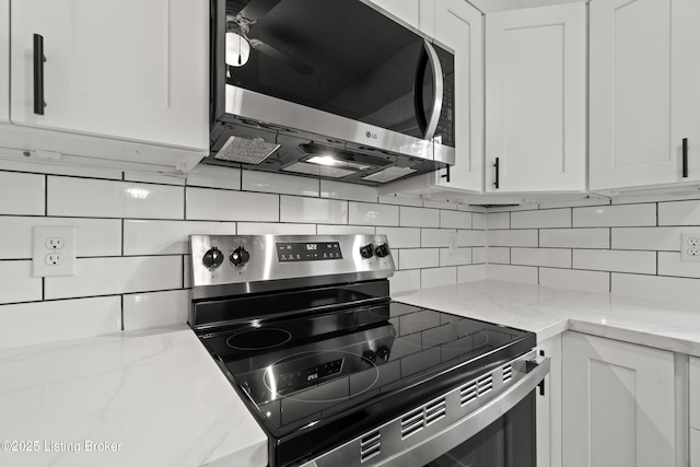 kitchen with appliances with stainless steel finishes, white cabinets, backsplash, and light stone counters