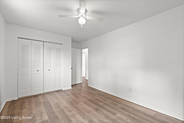 unfurnished bedroom with wood finished floors, baseboards, and a closet
