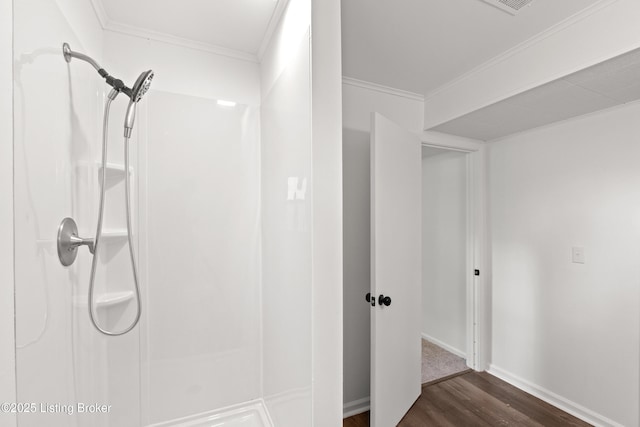 bathroom with a shower, wood finished floors, baseboards, and crown molding