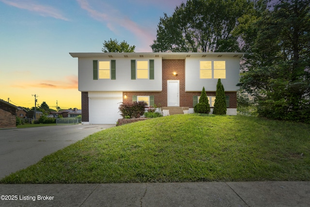 bi-level home with driveway, brick siding, an attached garage, and a front lawn