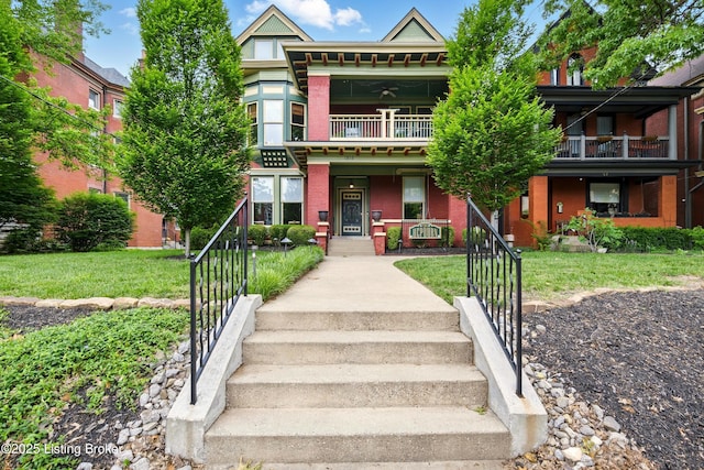 view of front facade with brick siding, a balcony, covered porch, and a front lawn