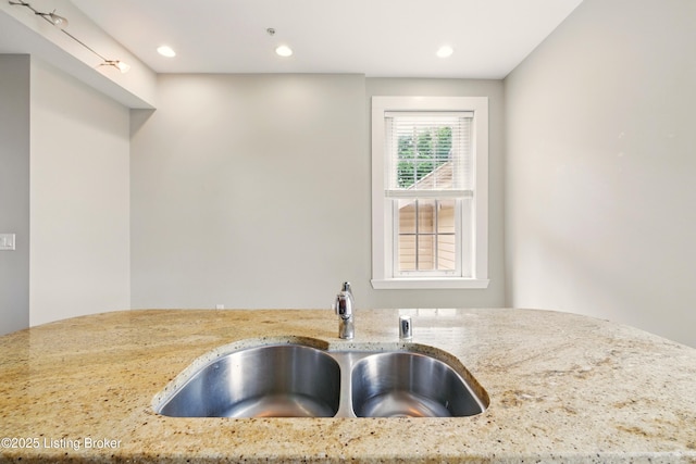 kitchen with a sink, light stone counters, and recessed lighting