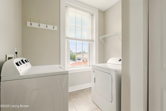 clothes washing area featuring independent washer and dryer, light tile patterned flooring, baseboards, and plenty of natural light