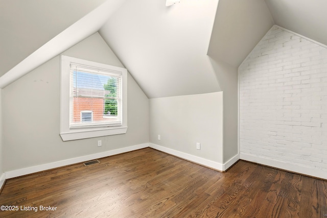 bonus room featuring brick wall, wood finished floors, vaulted ceiling, and baseboards