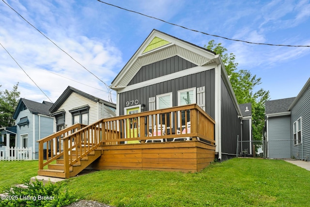 rear view of house featuring board and batten siding, a wooden deck, and a lawn