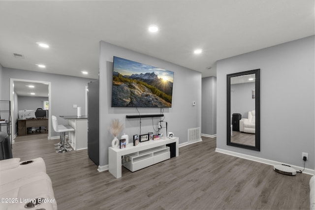 living area with recessed lighting, an office area, wood finished floors, and baseboards