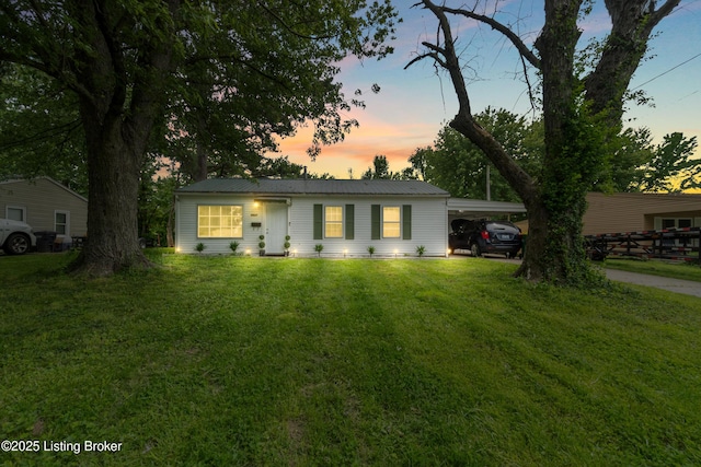 single story home featuring a front yard, metal roof, and a carport