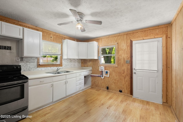 6614 Putman St, Louisville, KY 40216 - kitchen featuring stainless steel range with electric stovetop, plenty of natural light, a sink, white cabinets, and wood walls