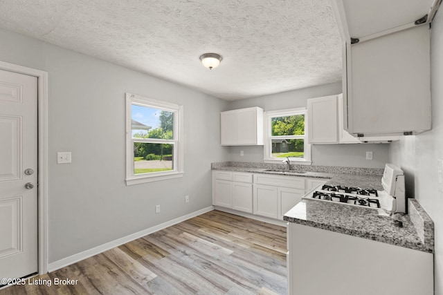 1037 Kaiser Ct, Louisville, KY 40211 - kitchen with a sink, stove, plenty of natural light, light wood-type flooring, and a textured ceiling