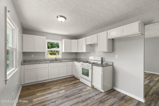 1037 Kaiser Ct, Louisville, KY 40211 - kitchen with white gas range, a sink, wood finished floors, dark stone counters, and white cabinets