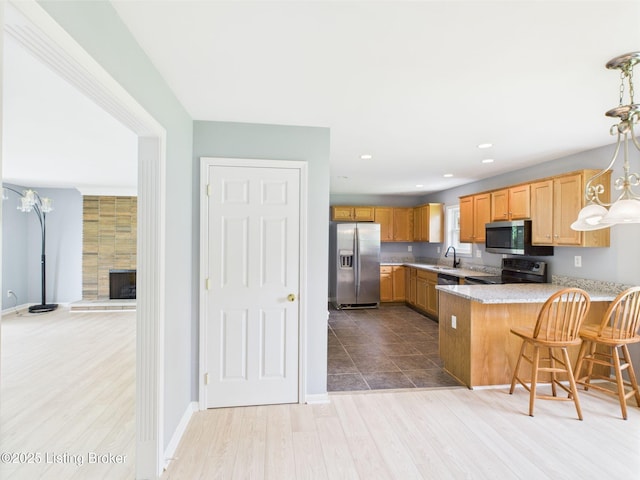 4212 David Ave, Louisville, KY 40215 - kitchen with stainless steel appliances, a sink, a peninsula, wood finished floors, and pendant lighting