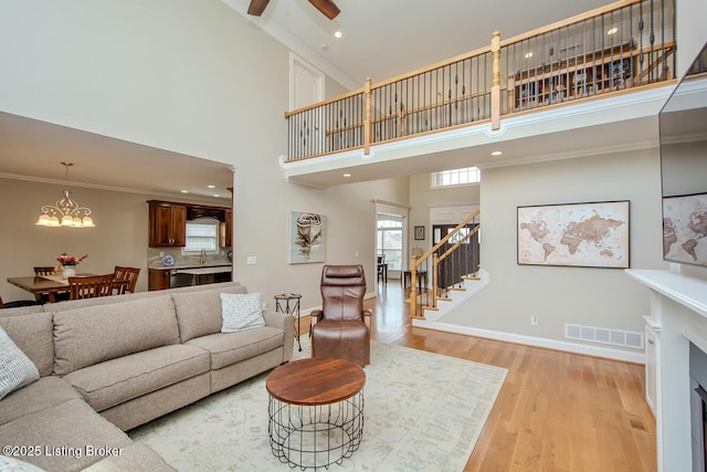 18705 Weymuth Ln, Louisville, KY 40245 - living area featuring a towering ceiling, stairs, a chandelier, light wood-style floors, and baseboards