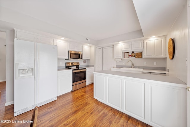 kitchen featuring stainless steel appliances, a sink, light countertops, white cabinetry, and recessed lighting